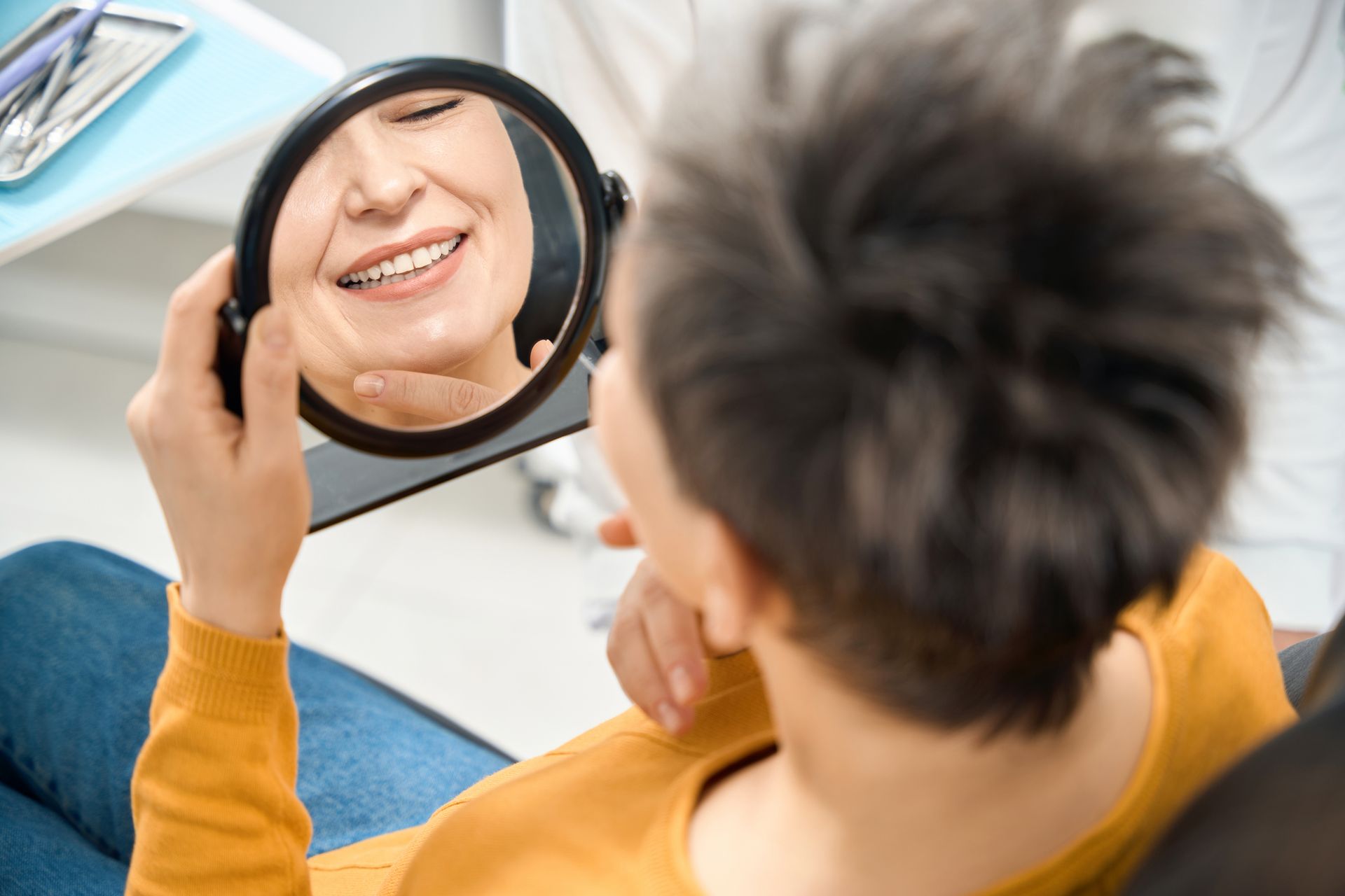 Woman checking her smile and state of teeth after smile makeover services.